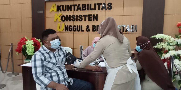 Ketua DPRD Kotamobagu, Meiddy Makalalag Saat Diukur Tekanan Darah Sebelum Divaksin di Mapolres Kotamobagu Oleh Petugas Covid-19.